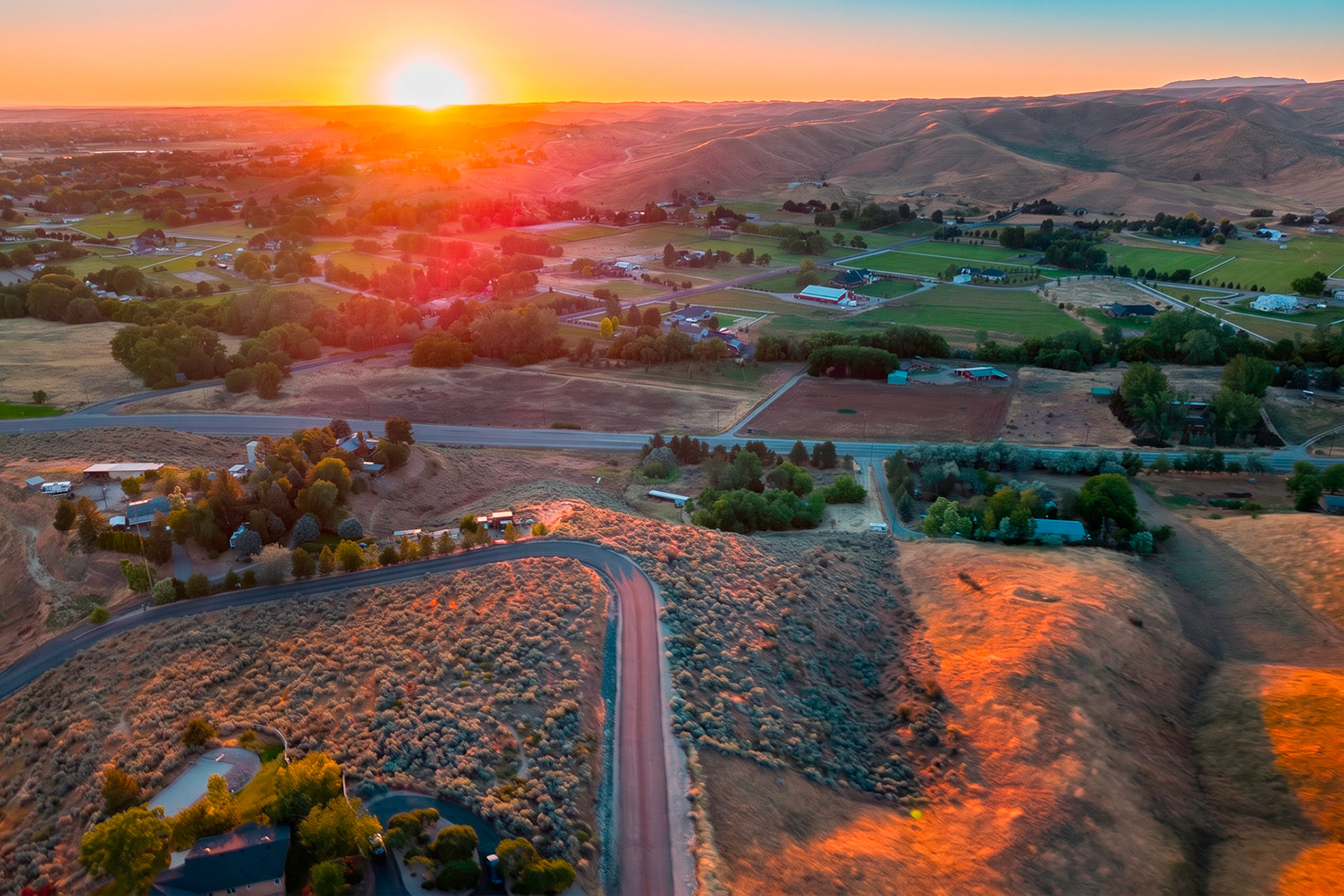 Golden-hour aerial of foothills and farmland at sunset